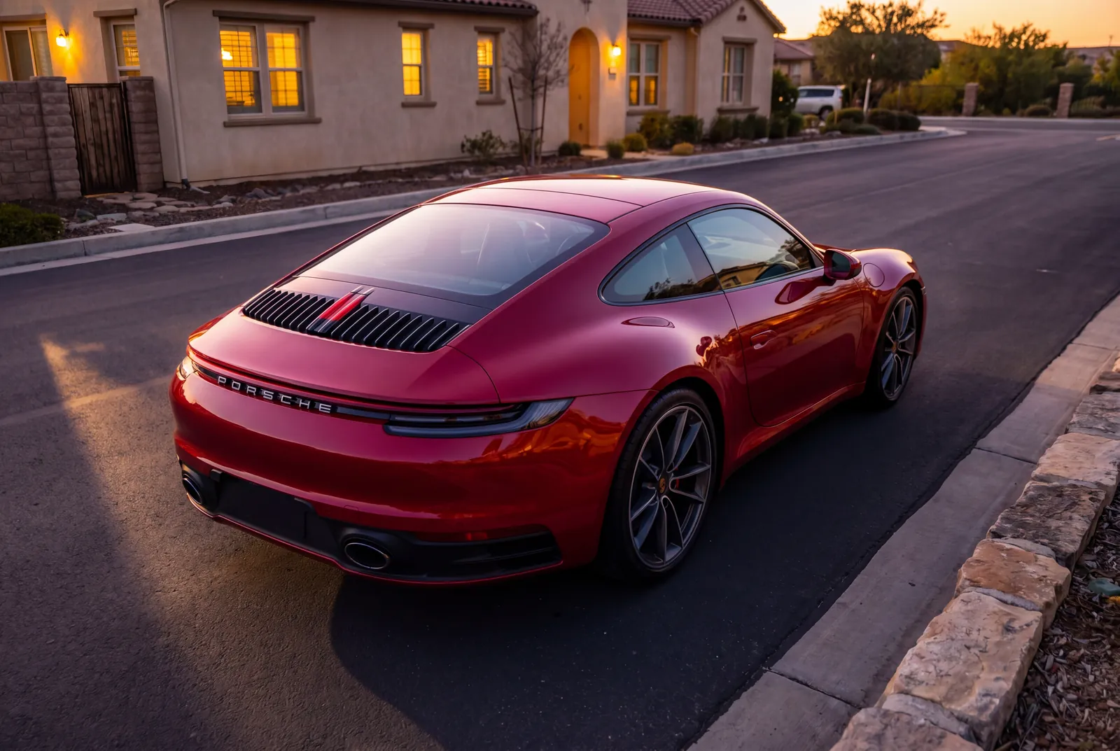 A freshly detailed red Porsche 911 parked on a residential driveway at golden hour